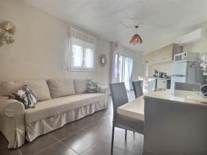 een woonkamer met een bank en een tafel en een keuken bij Charmant logement avec piscine in Le Cannet-des-Maures