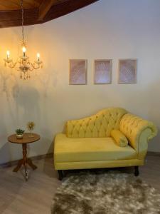 uma sala de estar com um sofá amarelo e uma mesa em Pousada Hinckel em Alfredo Wagner