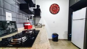 cocina con fogones y reloj en la pared en Infinite-WIFI-Garagem-Self check-in-Pet friendly, en Ribeirão Preto