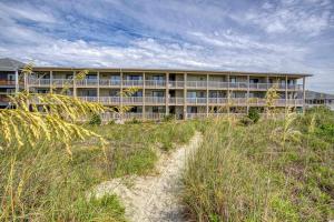 a building on the beach with a path in front at BEAUTIFUL BEACHFRONT-Oceanfront First Floor 2BR 2BA Condo in Cherry Grove, North Myrtle Beach! RENOVATED with a Fully Equipped Kitchen, 3 Separate Beds, Pool, Private Patio & Steps to the Sand! in Myrtle Beach