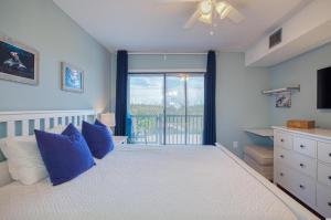 Un dormitorio con una cama con almohadas azules y una ventana en BEAUTIFUL BEACHFRONT-Oceanfront First Floor 2BR 2BA Condo in Cherry Grove, North Myrtle Beach! RENOVATED with a Fully Equipped Kitchen, 3 Separate Beds, Pool, Private Patio & Steps to the Sand! en Myrtle Beach