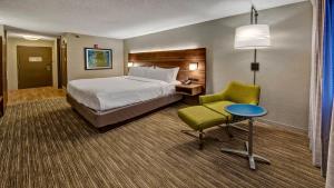 a hotel room with a bed and a chair and a table at Holiday Inn Express Louisville Airport Expo Center, an IHG Hotel in Louisville