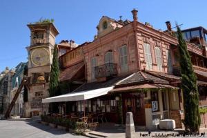 un antiguo edificio con una torre de reloj en una calle en Avlabari Apartment - NEW ONE, en Tiflis