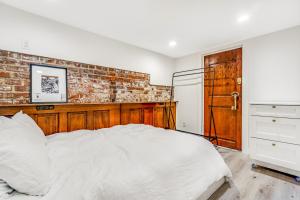 a white bed in a bedroom with a brick wall at The Studio in Seattle