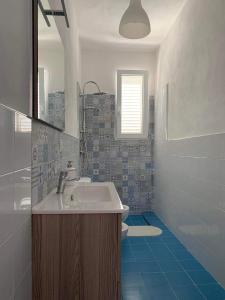 La salle de bains est pourvue d'un lavabo et d'un sol bleu. dans l'établissement Casa Simetite, à Granelli