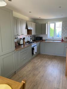 a kitchen with white cabinets and a wooden floor at Two bedroom house with enclosed gardens and 2 car drive in Caeʼr-geiliog