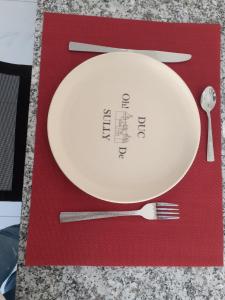 a white plate on a red napkin with a fork and knife at Appartement OH! Duc de Sully in Sully-sur-Loire