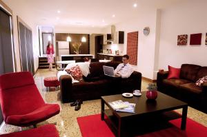 a man sitting on a couch with a laptop in a living room at Abode Bendigo Apartments in Bendigo