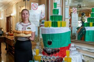 a woman holding a tray of food next to a cake at Karolina Hotel in Sunny Beach