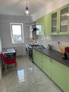 une cuisine avec des placards verts et un fauteuil rouge dans l'établissement Apartament Mara Centru, à Alba Iulia