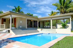 a house with a swimming pool in front of it at Bilene Brown House in Vila Praia Do Bilene