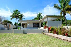 a house with palm trees in the background at Bilene Brown House in Vila Praia Do Bilene