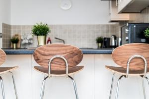 a kitchen with three wooden stools in front of a counter at Host & Stay - The Pall Mall Balcony Apt in Liverpool