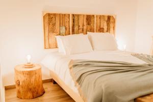 a bedroom with a large bed with a wooden headboard at Villa Saudade - Sustainable Living in Porto Covo