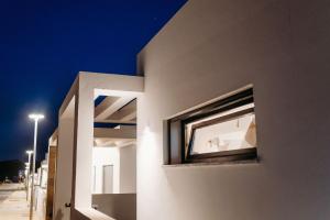 a window on the side of a building at night at Villa Saudade - Sustainable Living in Porto Covo