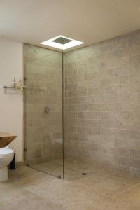 La salle de bains est pourvue d'une douche en verre et de toilettes. dans l'établissement Estancias Sierravita, à Valle de Guadalupe