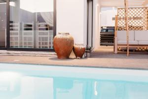 two vases are sitting next to a swimming pool at Villa Saudade - Sustainable Living in Porto Covo