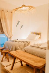 a bedroom with two beds and a wooden bench at Villa Saudade - Sustainable Living in Porto Covo