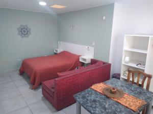 1 dormitorio con cama roja, mesa y sidra de mesa en Departamento 3 Complejo Sol de Oeste en San Juan