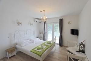 een slaapkamer met een wit bed, een bureau en een raam bij Villa Danica Murter in Betina