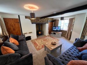 a living room with couches and a table and a tv at Braunston Manor Cottage in Braunston