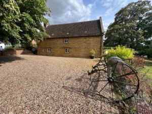 un edificio de ladrillo con una rueda delante de él en Braunston Manor Cottage en Braunston