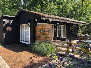 a black tiny house with a patio and flowers at Chalet Harmony in Zutendaal