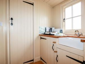 バッドにあるCornerpark Shepherds Hutの白いキャビネット、シンク、窓付きのキッチン