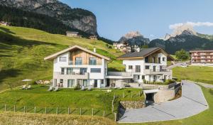 a large white house on a hill with mountains at Aurela Mountain Chalets in Selva di Val Gardena