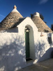 un pequeño edificio blanco con una puerta verde en Dimora Iconica, en Locorotondo