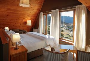 a bedroom with a bed and a large window at Los Cerros del Chaltén Boutique Hotel in El Chalten