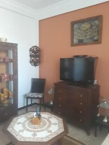a living room with a tv and a table with a candle at Bel Appartement Kouba Centre in Alger