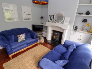a living room with two blue couches and a fireplace at Lime Cottage in Matlock