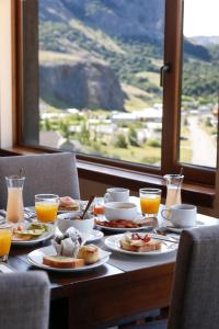 uma mesa com pratos de comida e copos de sumo de laranja em Los Cerros del Chaltén Boutique Hotel em El Chaltén
