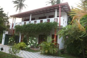 a white house with plants in front of it at Tithira Guest House in Mirissa