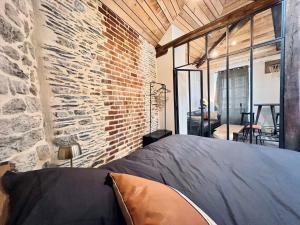 1 dormitorio con pared de ladrillo y 1 cama en una habitación en Les Suites de la Tour d'Embas, en Vitré