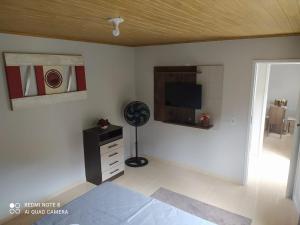 Dieses weiße Zimmer verfügt über einen Ventilator und einen TV an der Wand. in der Unterkunft APARTAMENTO DU VÔ - Cantinho Du Vô in Santa Teresa