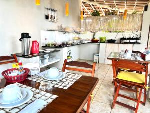 AYRE GOSTOSO POUSADA في ساو ميجيل دو غوستوسو: مطبخ مع طاولة وكراسي خشبية ومطبخ مع كونتر