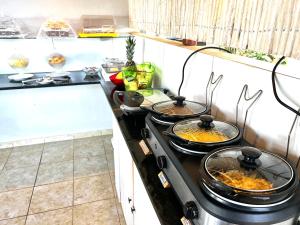 a kitchen with four pans of food on a stove at AYRE GOSTOSO POUSADA in São Miguel do Gostoso