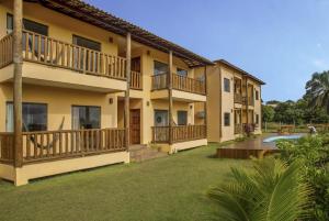 a large apartment building with balconies and a yard at Camboa Village in Barra Grande