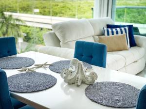uma mesa branca com cadeiras azuis e um sofá branco em Apartamento Cartagena en Morros frente a la playa em Cartagena das Índias
