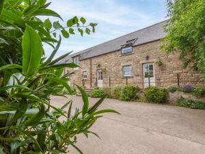 ein altes Backsteingebäude mit einer Einfahrt davor in der Unterkunft Jenny's Cottage in Alnwick