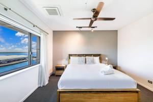 a bedroom with a bed and a large window at Top of Timor Sea A Luxury Waterfront Penthouse in Darwin