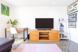 a living room with a tv on a wooden entertainment center at Darwin Waterfront Lagoon Hideaway with Sea Views in Darwin