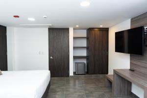 1 dormitorio con 1 cama y TV de pantalla plana en Hotel Qatar Cali, en Cali