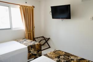a room with two beds and a tv on the wall at EL BORSALINO - Apartamento en Amazonas, Leticia in Leticia