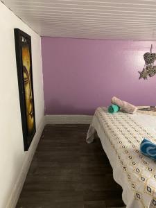 1 dormitorio con 1 cama con pared morada en Campêche en Fort-de-France