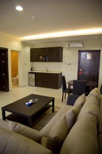sala de estar con sofá, mesa y cocina en Al Nakhlah Furnished Units, en Al Hofuf