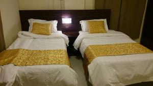 Habitación con 2 camas y sábanas blancas y amarillas. en Al Nakhlah Furnished Units, en Al Hofuf