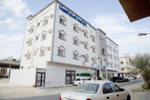 a white building with a car parked in front of it at Al Nakhlah Furnished Units in Al Hofuf
